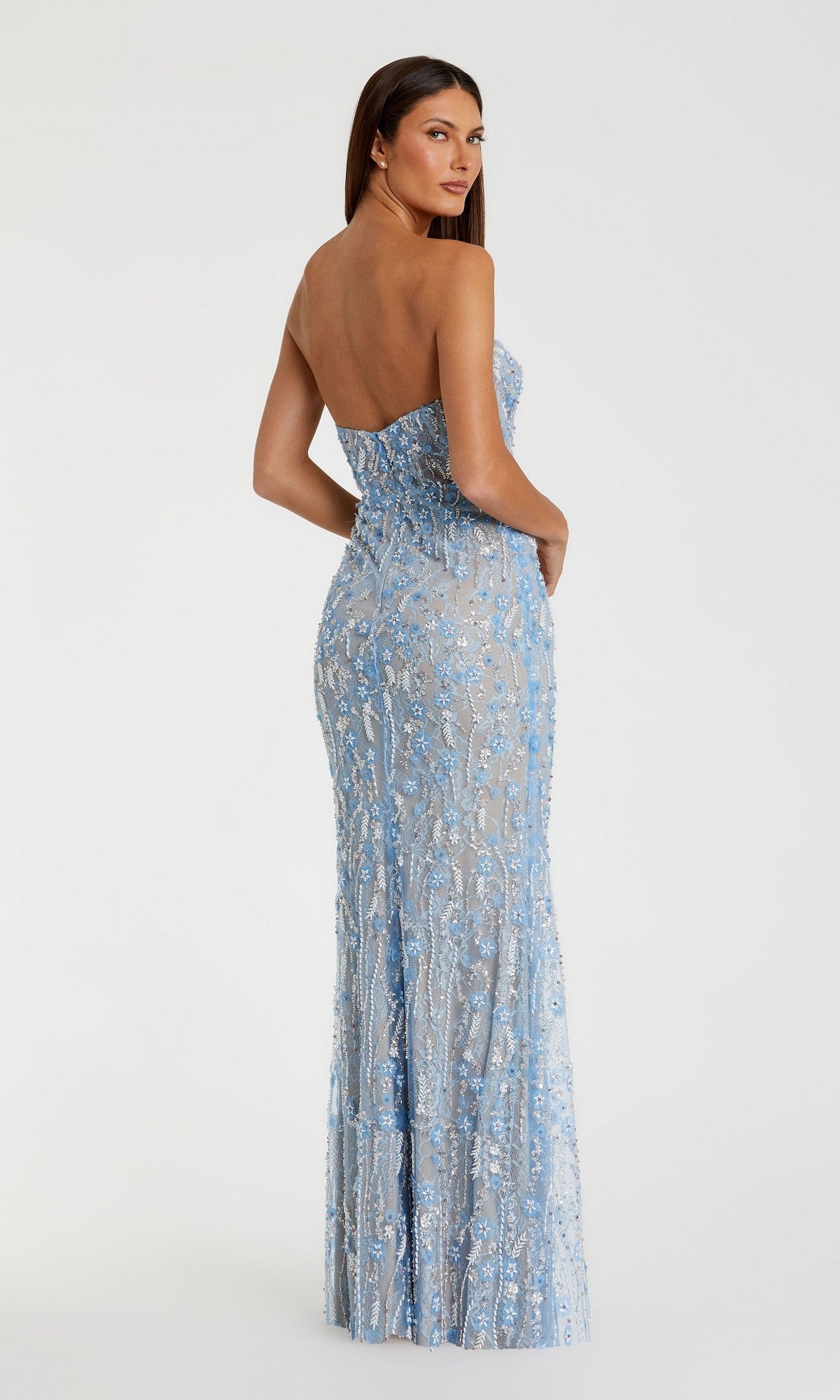 Model wearing the Mac Duggal 68893 Long Formal Dress, a strapless, floor-length fitted blue gown featuring sequin embellishments and delicate floral beadwork, posed standing and looking over her shoulder against a plain white background.